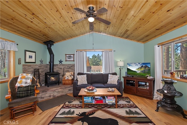 living room featuring wood ceiling, ceiling fan, a wood stove, vaulted ceiling, and wood finished floors