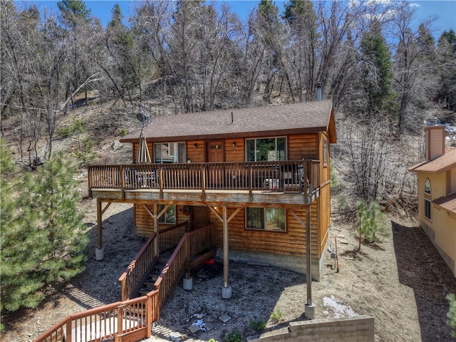 rear view of house with stairway, log veneer siding, a wooden deck, and a shingled roof