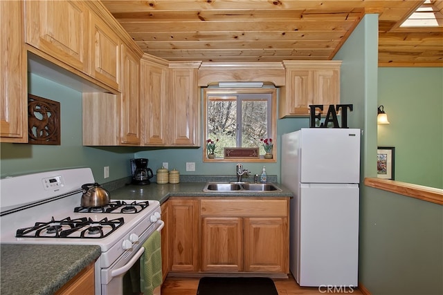 kitchen with dark countertops, a sink, light wood-style floors, white appliances, and wooden ceiling
