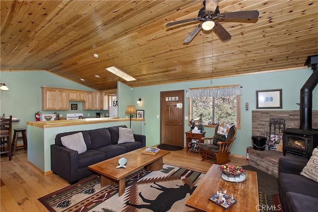 living area featuring a wood stove, light wood finished floors, ceiling fan, and lofted ceiling