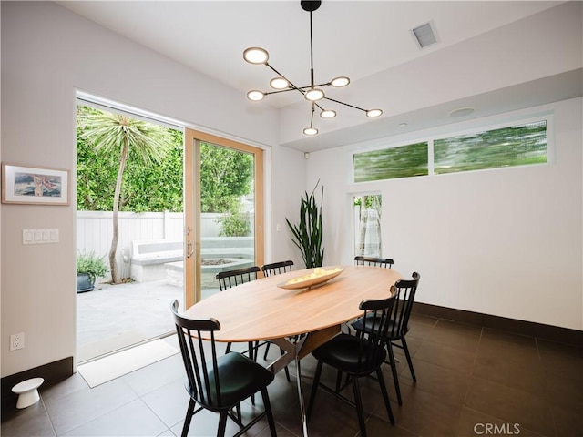 dining room with a healthy amount of sunlight, an inviting chandelier, dark tile patterned flooring, and visible vents
