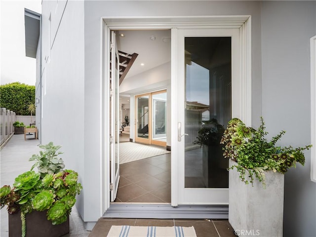 view of exterior entry with fence and stucco siding