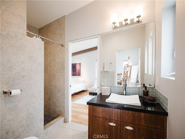 ensuite bathroom featuring tile patterned floors, vanity, ensuite bath, and tiled shower