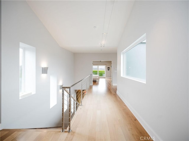 corridor featuring an upstairs landing and light wood-style flooring