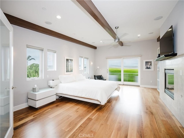 bedroom featuring a tile fireplace, access to outside, beam ceiling, and light wood-type flooring