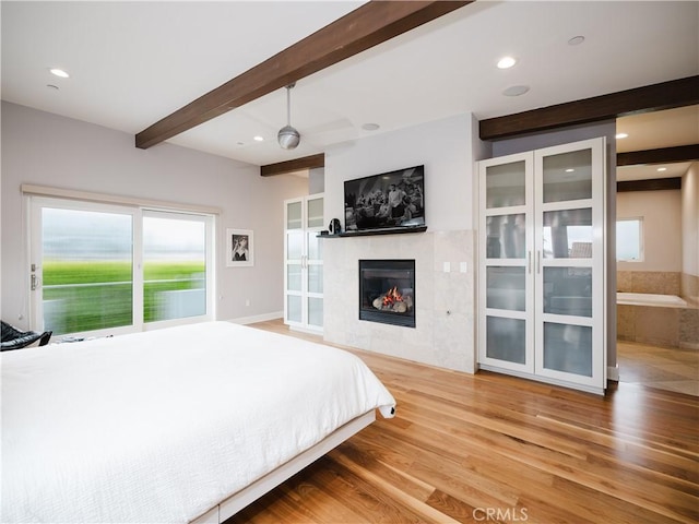 bedroom with beamed ceiling, a fireplace, recessed lighting, and wood finished floors