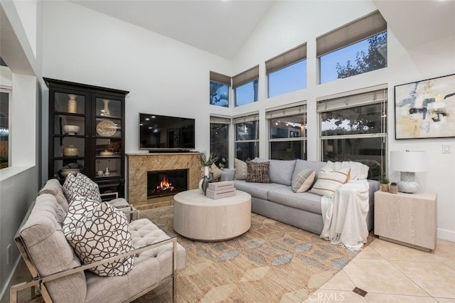 tiled living room featuring high vaulted ceiling, baseboards, and a premium fireplace