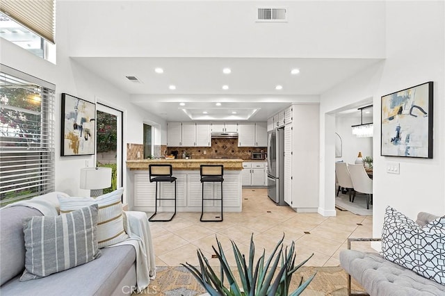 living area featuring recessed lighting, light tile patterned floors, and visible vents