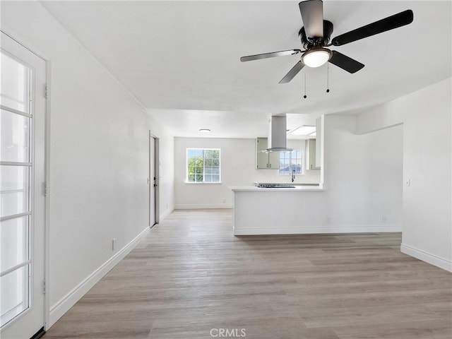 unfurnished living room featuring baseboards, ceiling fan, and light wood finished floors