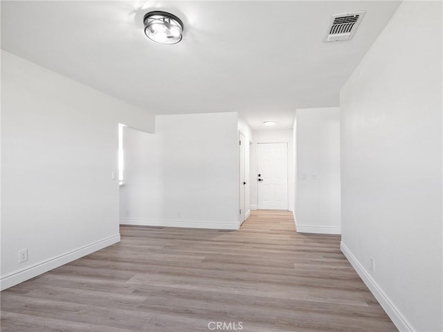 spare room with baseboards, visible vents, and light wood-style floors