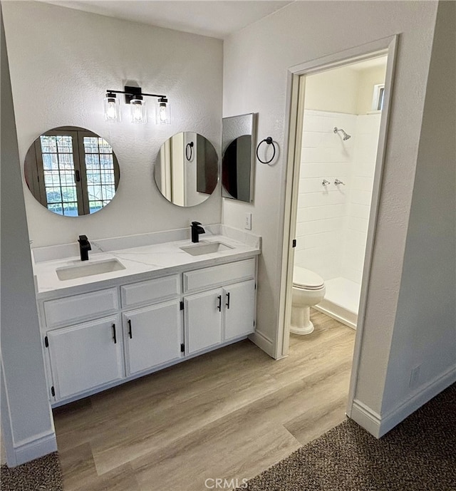 bathroom with a sink, wood finished floors, and tiled shower