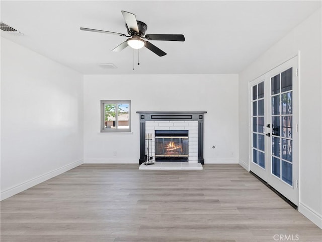 unfurnished living room featuring a brick fireplace, french doors, baseboards, wood finished floors, and visible vents