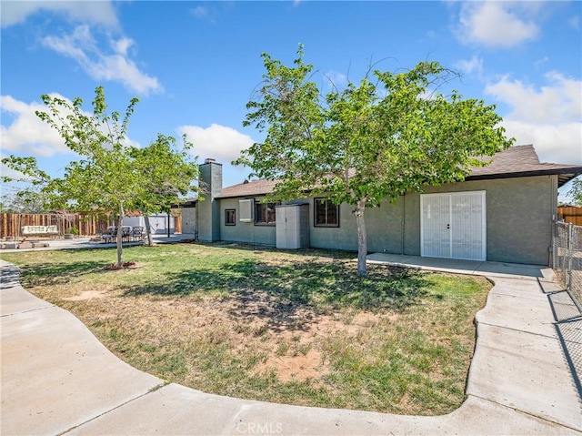 view of front of house featuring fence, a chimney, a front lawn, and stucco siding