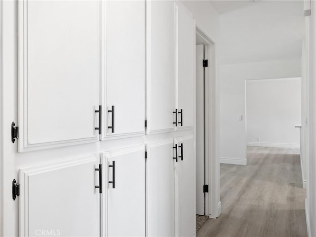 corridor with baseboards and light wood-type flooring