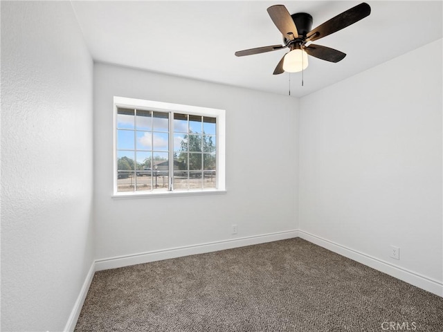 empty room with baseboards, ceiling fan, and dark carpet