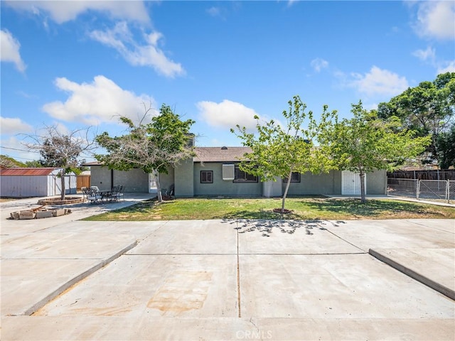 single story home featuring an outdoor structure, a front lawn, fence, a patio, and a shed