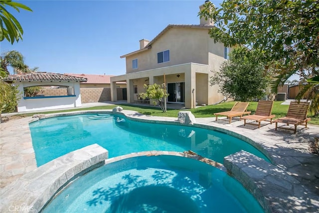 view of pool with fence, a pool with connected hot tub, and a patio area