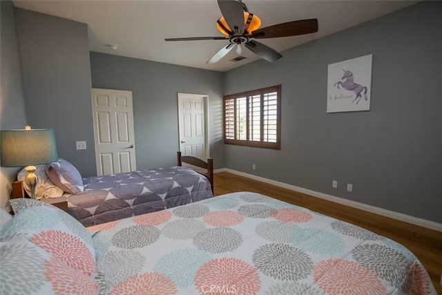 bedroom featuring visible vents, a closet, wood finished floors, baseboards, and a ceiling fan