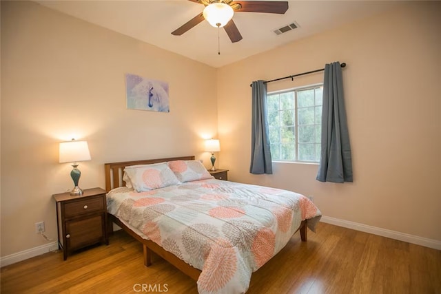 bedroom featuring baseboards, a ceiling fan, wood finished floors, and visible vents