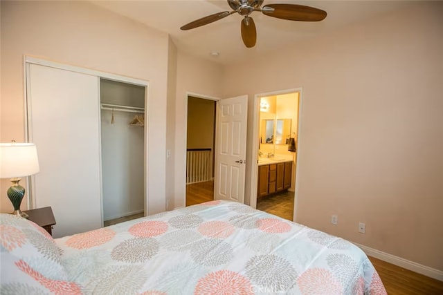 bedroom with a closet, wood finished floors, baseboards, ensuite bathroom, and ceiling fan