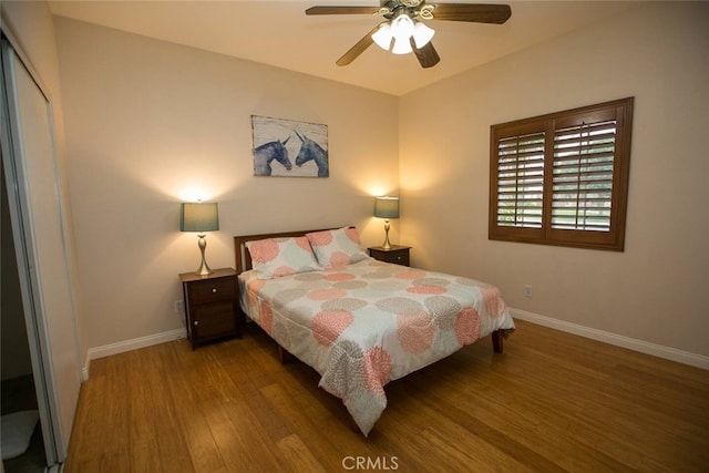 bedroom featuring baseboards, ceiling fan, wood finished floors, and a closet