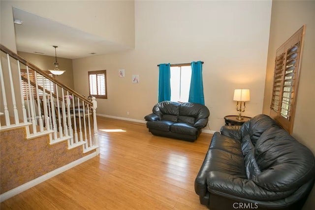 living area with stairs, baseboards, and light wood-type flooring