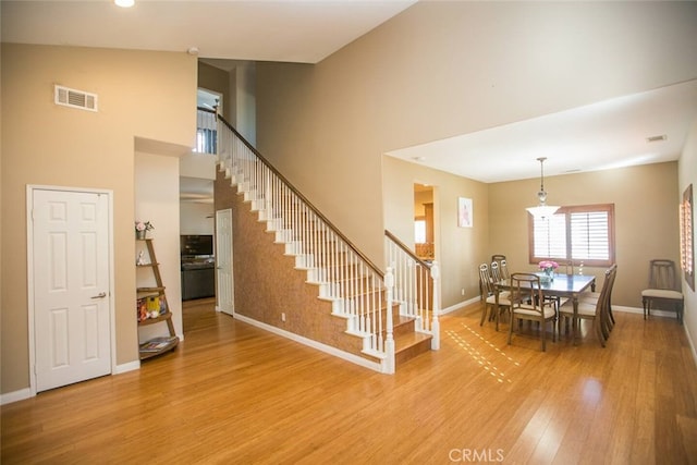 interior space featuring light wood-type flooring, baseboards, visible vents, and stairway