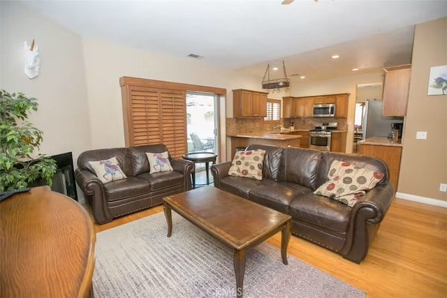 living area with recessed lighting, baseboards, light wood-type flooring, and visible vents