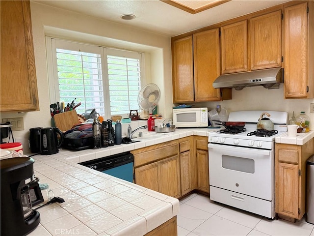 kitchen featuring brown cabinets, a sink, white appliances, tile countertops, and under cabinet range hood