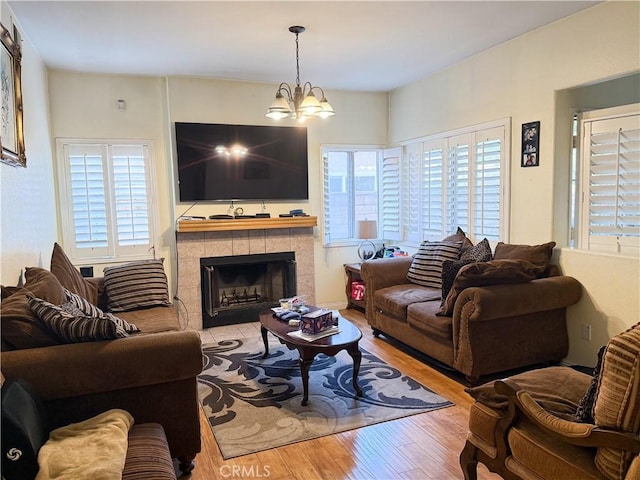 living area with a chandelier, wood finished floors, and a tile fireplace