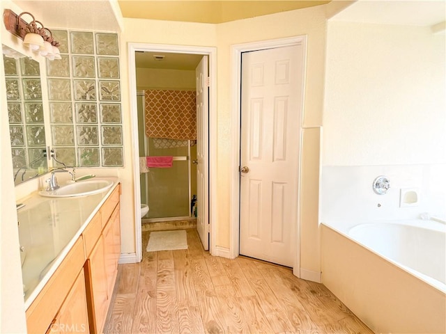 full bath with vanity, wood finished floors, a bath, and a stall shower