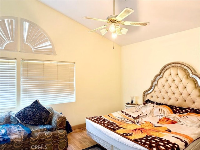 bedroom featuring baseboards, multiple windows, vaulted ceiling, and wood finished floors
