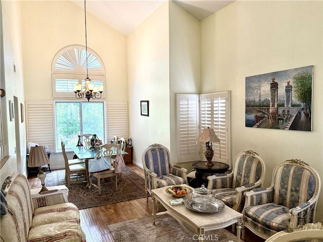 living room featuring baseboards, wood finished floors, a notable chandelier, and high vaulted ceiling