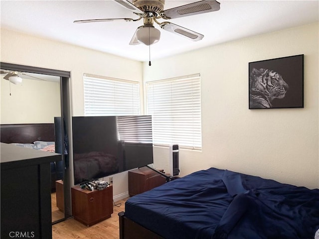 bedroom featuring light wood-type flooring, a ceiling fan, and multiple windows