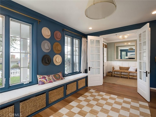 interior space with wainscoting, ornamental molding, french doors, and light wood-type flooring