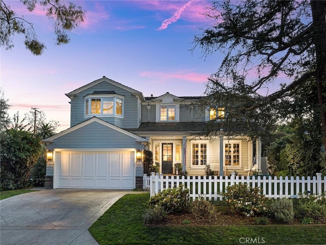 traditional home featuring a garage, a fenced front yard, and driveway