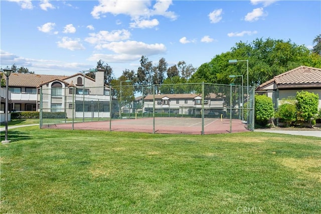 view of tennis court featuring fence, a yard, and community basketball court