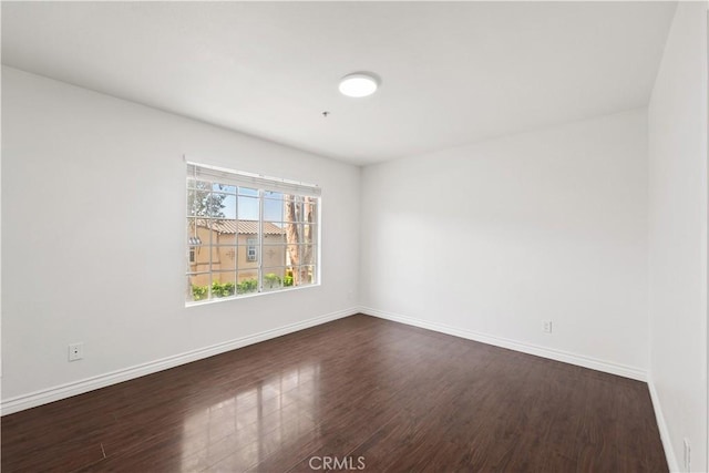 empty room featuring baseboards and dark wood-type flooring