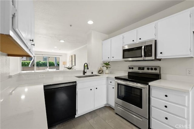 kitchen with appliances with stainless steel finishes, a sink, light countertops, white cabinets, and recessed lighting