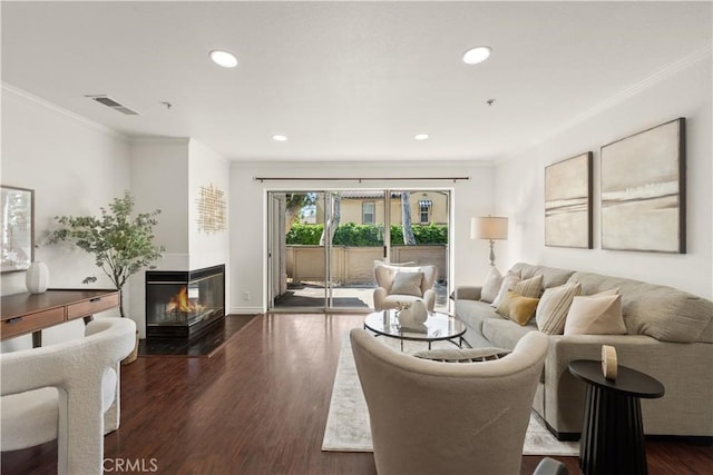 living room featuring a multi sided fireplace, visible vents, dark wood finished floors, ornamental molding, and recessed lighting