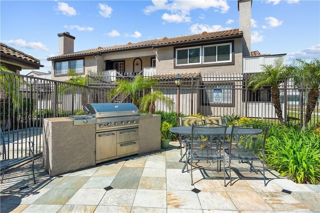 view of patio / terrace featuring fence, exterior kitchen, outdoor dining area, and area for grilling