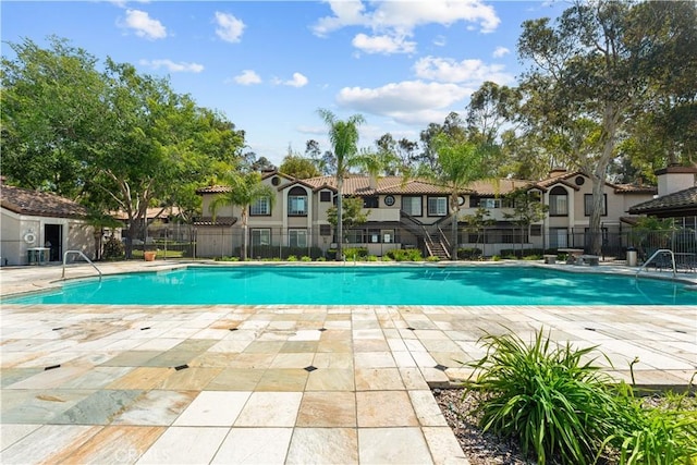 pool featuring a patio, fence, and a residential view