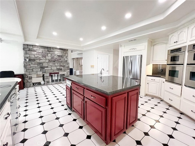 6926 Orozco Dr, Riverside, CA 92506 - kitchen with appliances with stainless steel finishes, a sink, light floors, reddish brown cabinets, and a tray ceiling