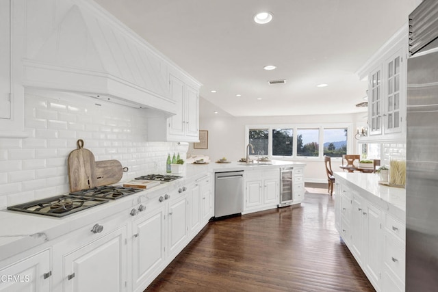 kitchen featuring decorative backsplash, appliances with stainless steel finishes, white cabinets, a peninsula, and wine cooler