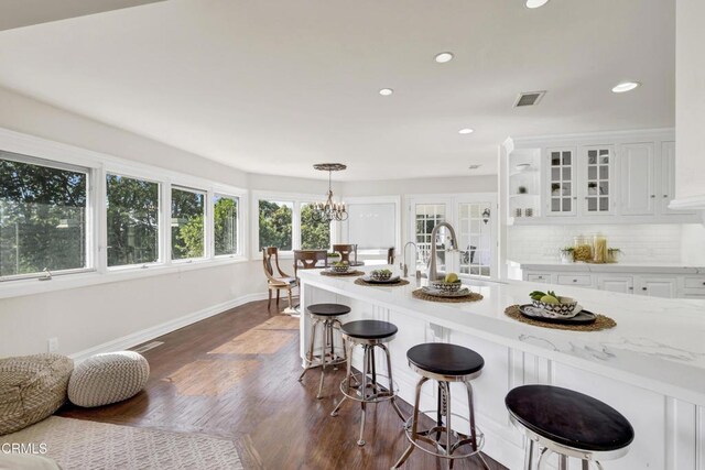 kitchen featuring a kitchen bar, recessed lighting, white cabinetry, a sink, and dark wood finished floors