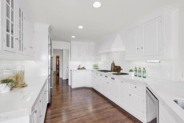 kitchen with dark wood-style flooring, tasteful backsplash, white cabinetry, premium range hood, and white gas stovetop