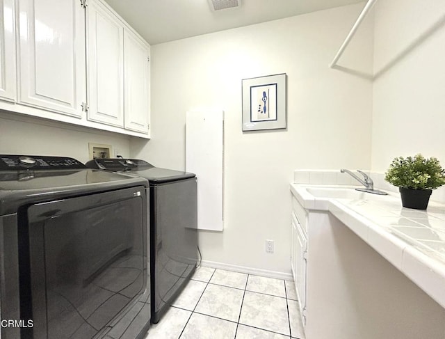 laundry area with light tile patterned flooring, baseboards, washer and clothes dryer, a sink, and cabinet space