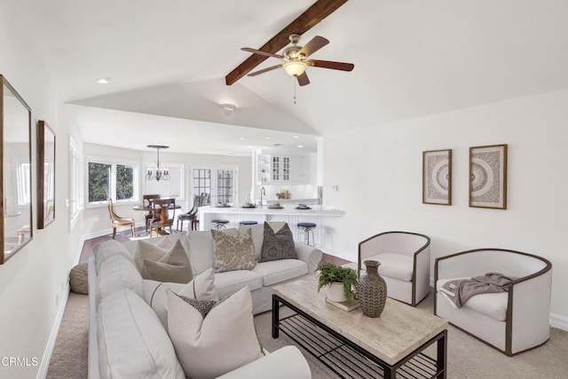living room with baseboards, light carpet, vaulted ceiling with beams, and ceiling fan with notable chandelier