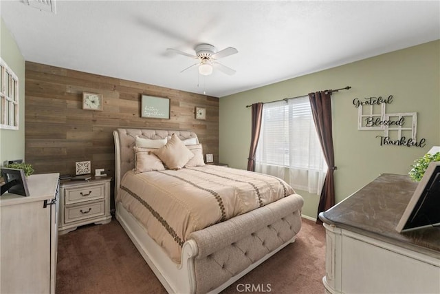 bedroom with a ceiling fan, wood walls, dark carpet, and visible vents