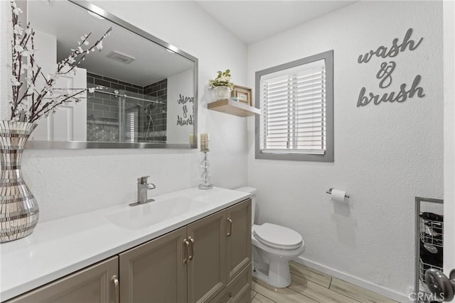 full bath featuring vanity, toilet, baseboards, a shower stall, and wood finished floors